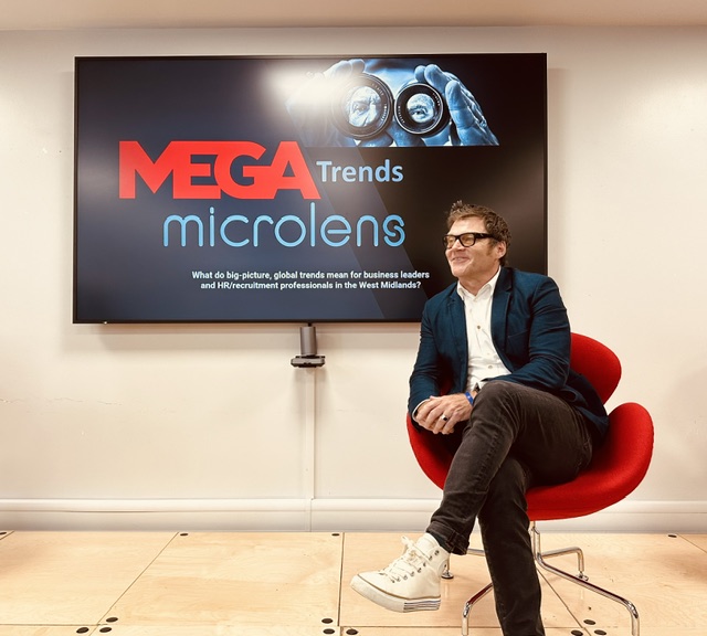 Tom Hadley seated beside a screen displaying MEGA Trends microlens